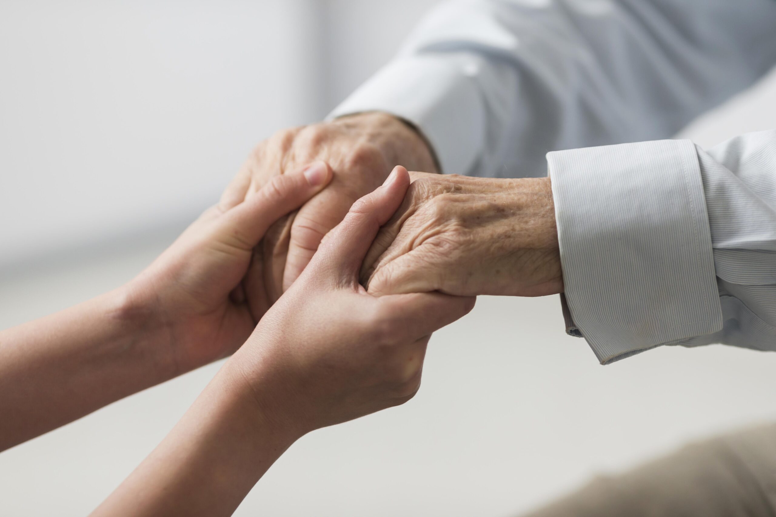 Young hand holding elderly hand, symbolizing care and support for aging family members